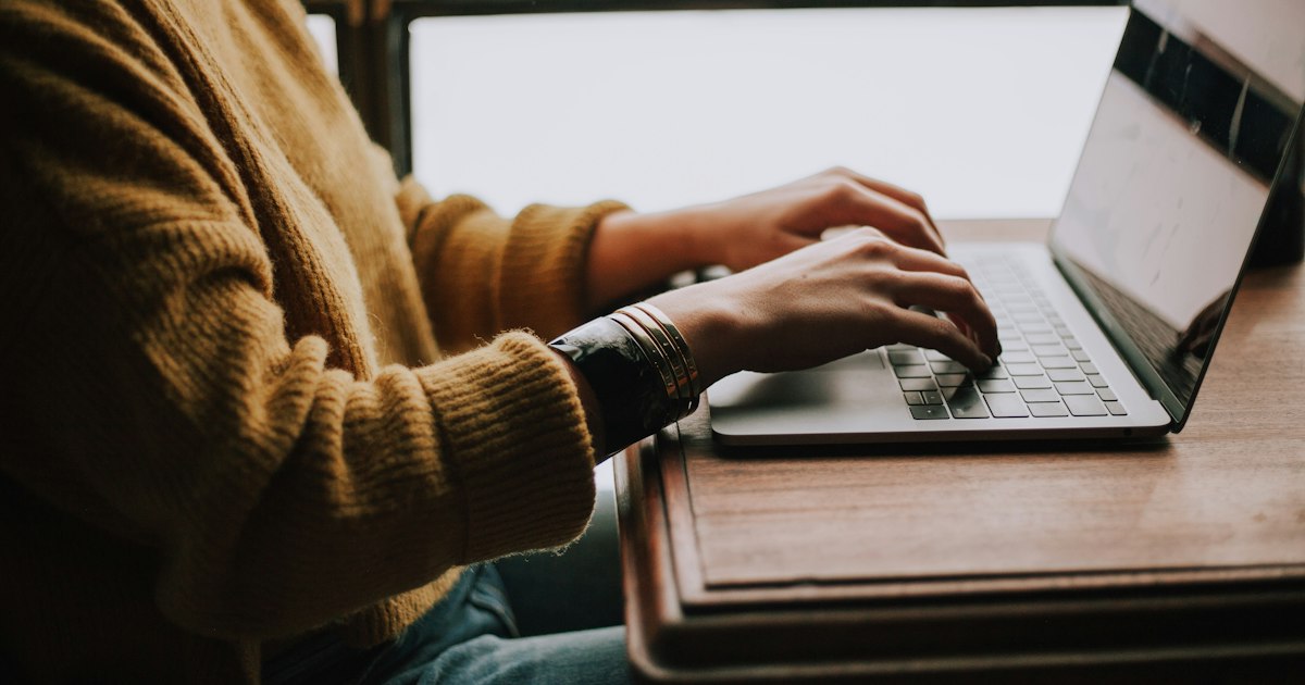 Professional typing on a laptop keyboard in a modern office workspace
