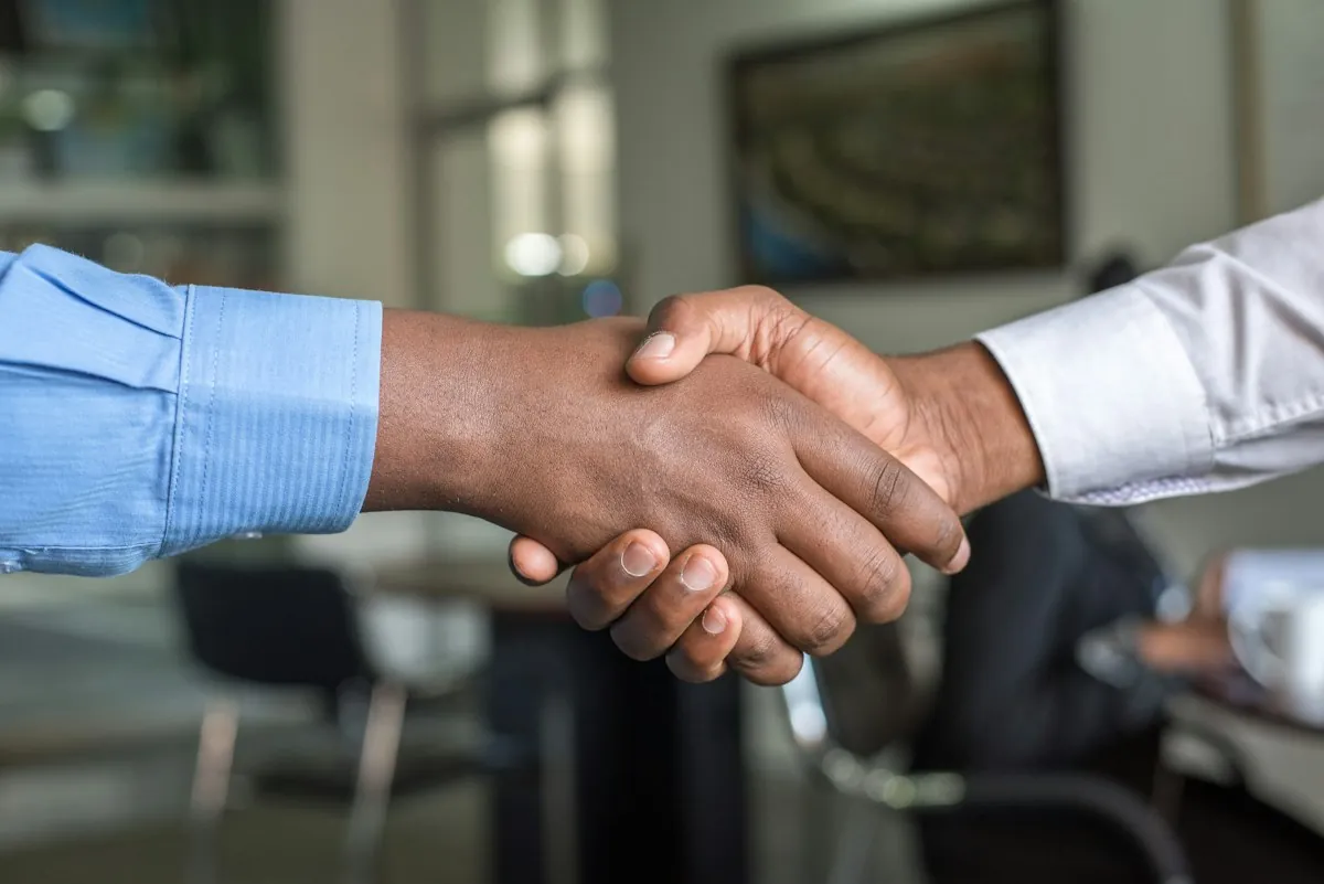 Business professionals shaking hands over a signed agreement
