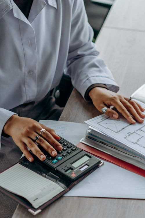 An accountant reviewing financial documents with a calculator at an organized office desk